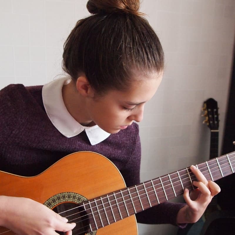 Young woman with her hair up playing guitar