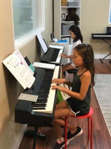 Two girls playing keyboards side by side
