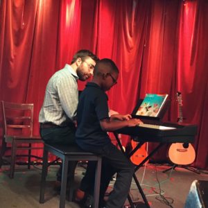 Man and a boy sitting together and playing a keyboard