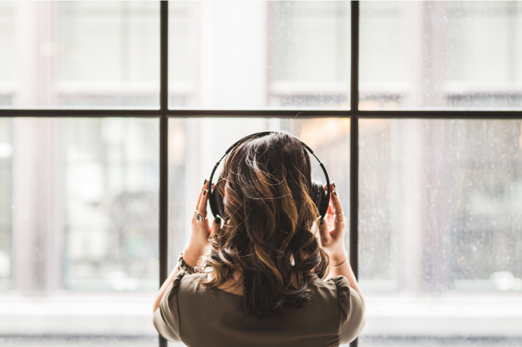 Picture of a woman from the back, shoulder length dark hair, wearing head phones