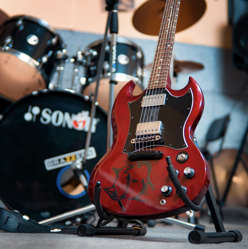 Screen-Shot-2022-06-01-at-10.52.12-AM | Highland Music Studio Red and black electric guitar positioned in front of a black drum set