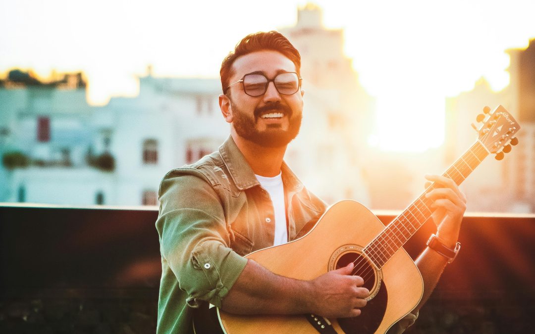 happy adult man playing guitar outside